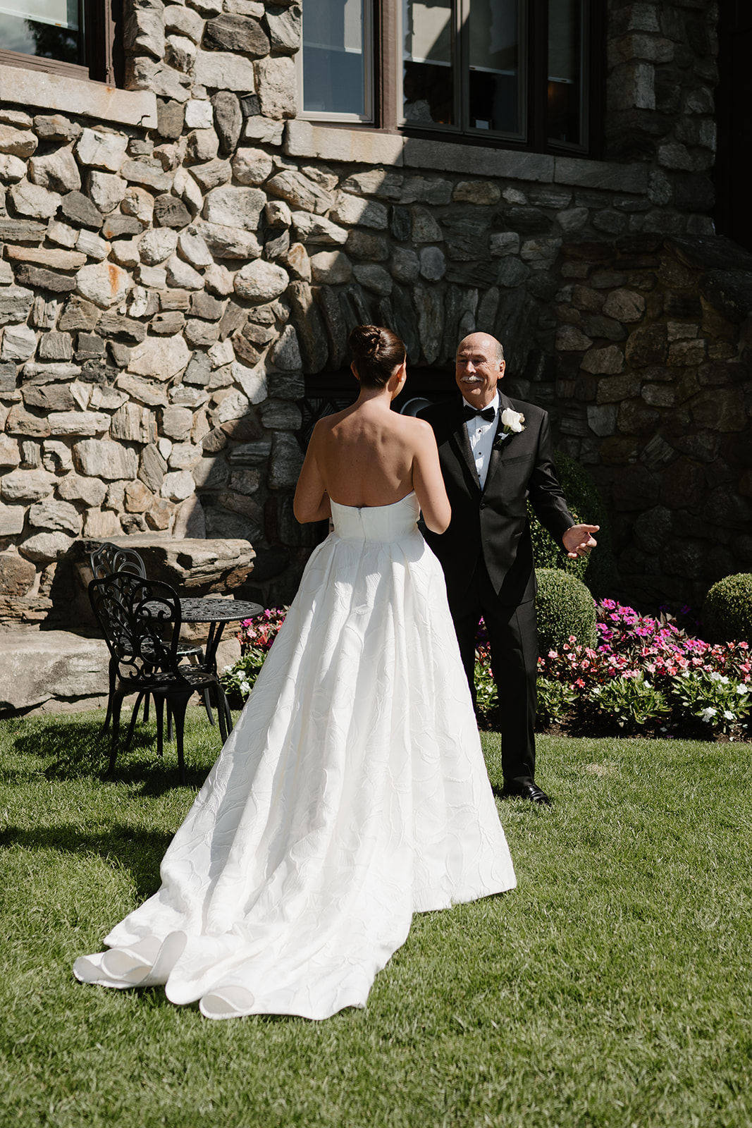Smiling father warmly greeting his daughter during an emotional first look by a stone wall.